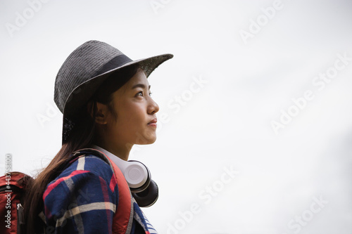 Young traveler woman in hipster style with backpack and hat standing looking the sky