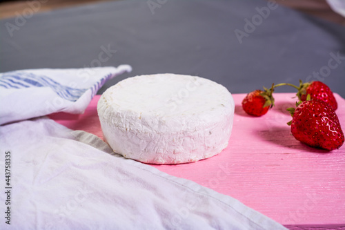 Camembert with strawberries with mint on a pink wooden board on a grey background 