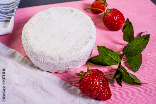Camembert with strawberries with mint on a pink wooden board on a grey background 