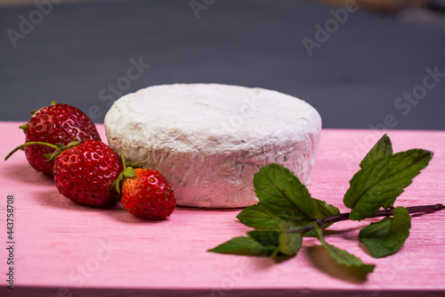 Camembert with strawberries with mint on a pink wooden board on a grey background 
