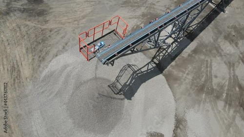 aerial drone shot of stone crusher machine in sunny day. small size stones are falling down on the ground from the conveyer belt photo