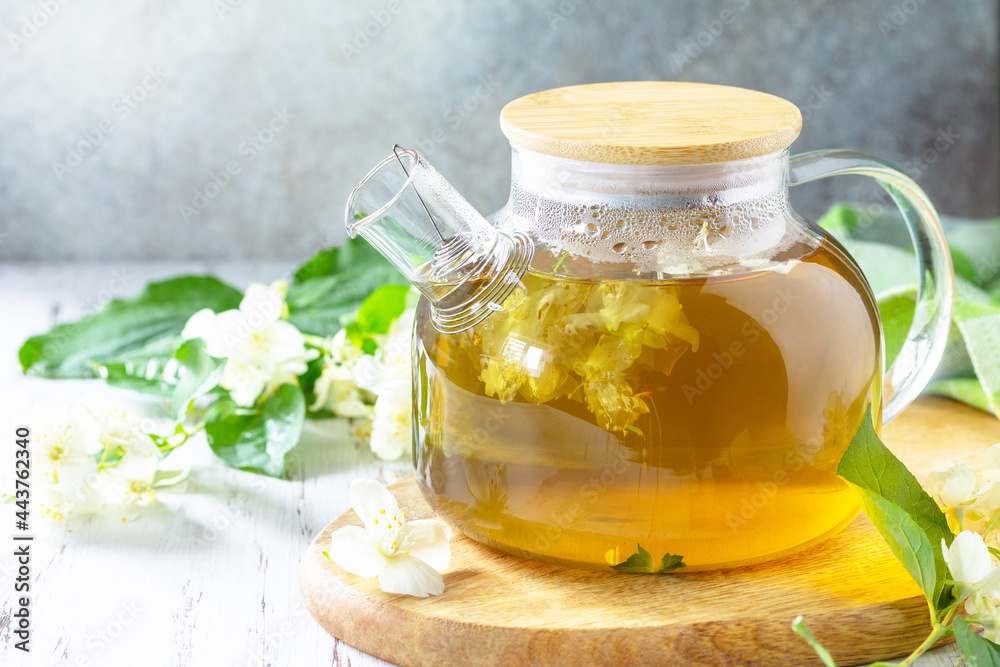 Therapeutic herbal tea. Hot Jasmine tea with jasmine flowers in a glass teapot on a rustic wooden table. Copy space. Therapeutic herbal tea. Hot Jasmine tea with jasmine flowers in a glass teapot on a rustic wooden table. Copy space.
