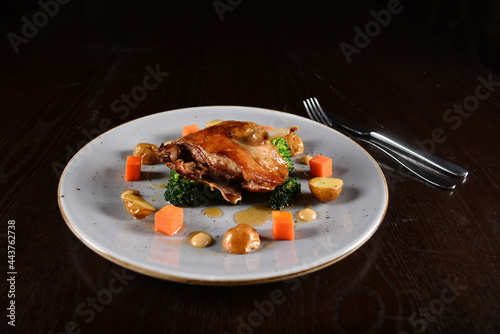 marinated grilled duck leg confit with vegetables and sauce main course in dark background western halal menu photo