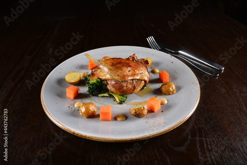 marinated grilled duck leg confit with vegetables and sauce main course in dark background western halal menu photo
