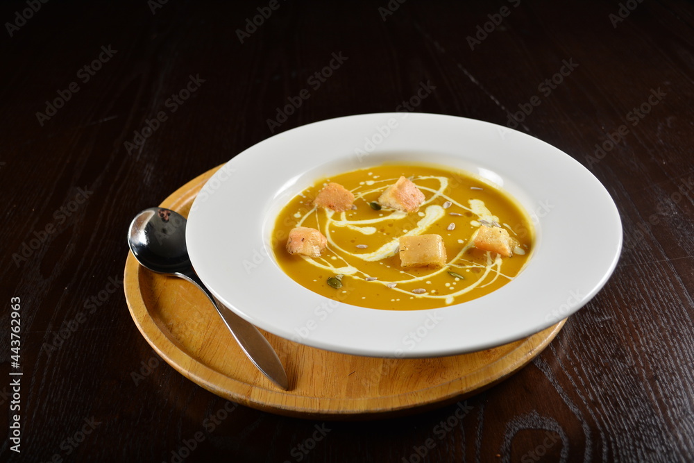 fresh cook golden yellow pumpkin thick soup with bread spread bites and cream appetiser in dark background western halal menu fresh cook golden yellow pumpkin thick soup with bread spread bites and cream appetiser in dark background western halal menu