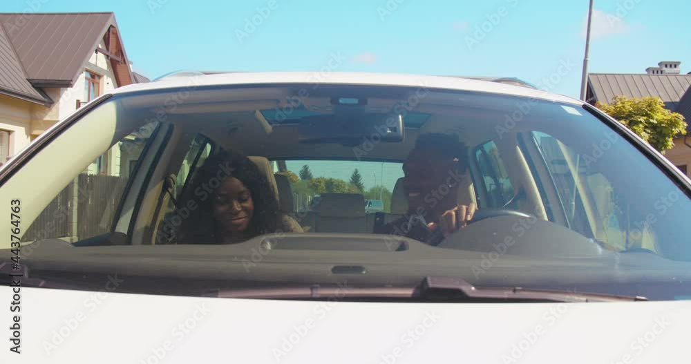 Front view of the charming multiracial lady and her boyfriend riding at the car and smiling while chatting with each other during the sunny day. Transport and people concept Front view of the charming multiracial lady and her boyfriend riding at the car and smiling while chatting with each other during the sunny day. Transport and people concept