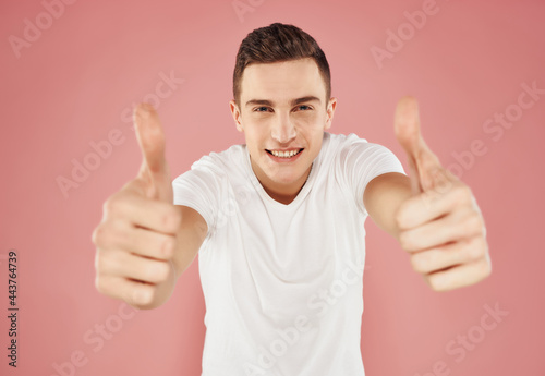 emotional man gesturing with his hands in a white t-shirt pink background close-up © SHOTPRIME STUDIO