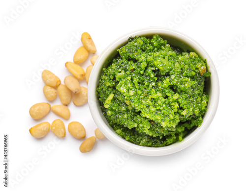 Bowl with fresh pesto sauce and pine nuts on white background