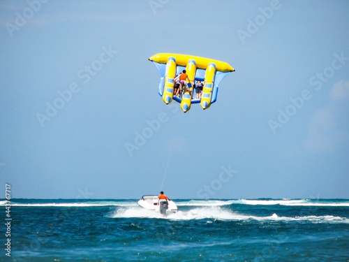 Flying fish water sport activity in Tanjung Benoa, Bali, Indonesia. Popular tourist attraction. Clear blue sky with horizon in background.
