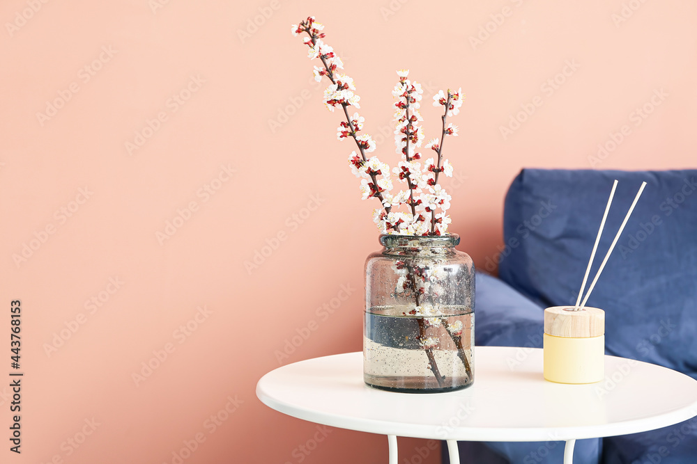 Vase with blooming spring branches on table in room Vase with blooming spring branches on table in room