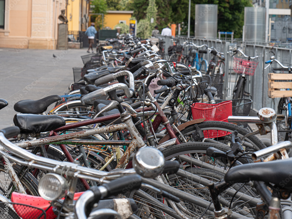 Many old Bicycles Padlocked to the Rack near Train Station Many old Bicycles Padlocked to the Rack near Train Station