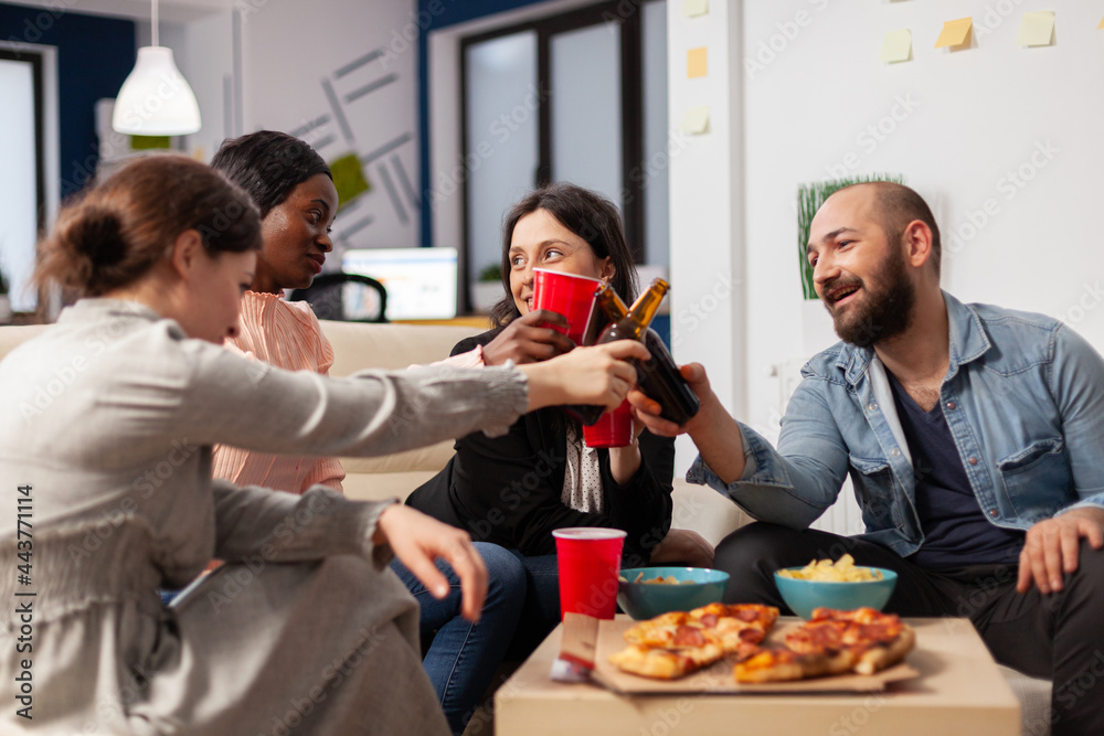 Diverse group of workers having fun after work at office meeting party. Cheerful friends cheers bottles and cups of beer to celebrate break from business. Multi ethnic people smiling Diverse group of workers having fun after work at office meeting party. Cheerful friends cheers bottles and cups of beer to celebrate break from business. Multi ethnic people smiling