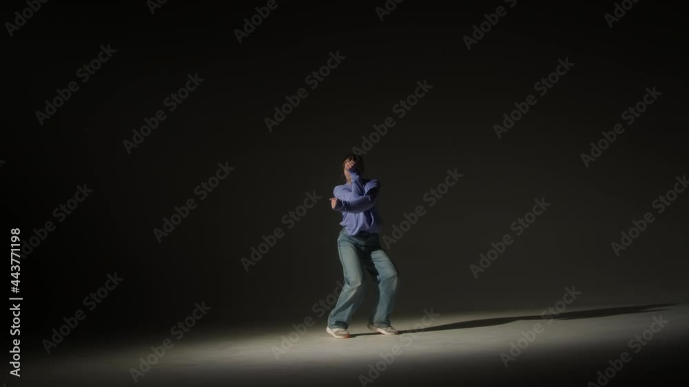 Talented woman dancing hip hop on dark background in studio. Shooting of modern choreography for advertising of dance school, dancer expressing feelings for music video performance. Talented woman dancing hip hop on dark background in studio. Shooting of modern choreography for advertising of dance school, dancer expressing feelings for music video performance.