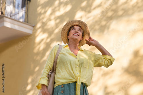 happy senior woman in sun hat walks  on summer city photo