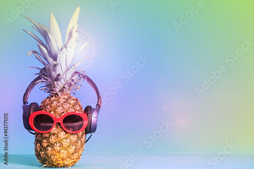 Pineapple with headphones and sunglasses on color background, space for text. Summer party