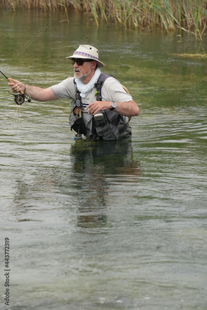 fly fisherman fishing in a small wild river fly fisherman fishing in a small wild river