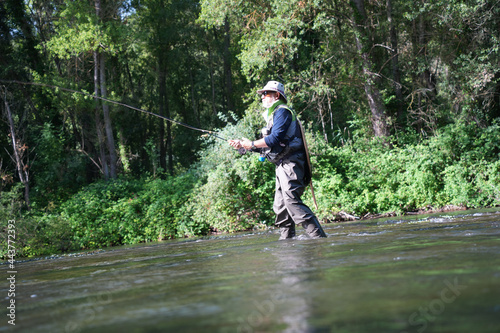 fly fisherman fishing in a small wild river