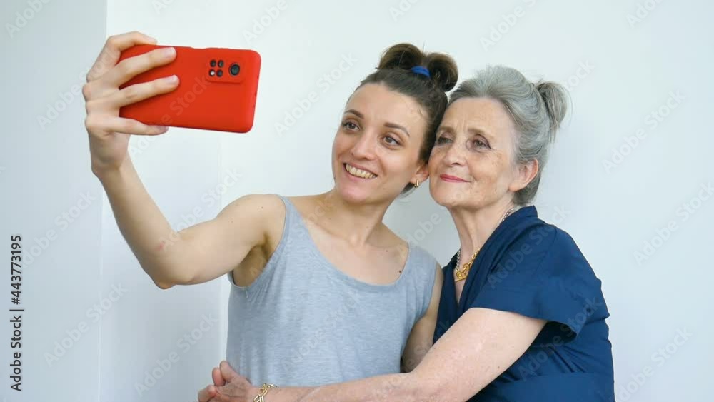 Adult daughter and senior mum are taking self-portrait picture, selfie on red smartphone together, happy retirement, mothers day concepts. Adult daughter and senior mum are taking self-portrait picture, selfie on red smartphone together, happy retirement, mothers day concepts.