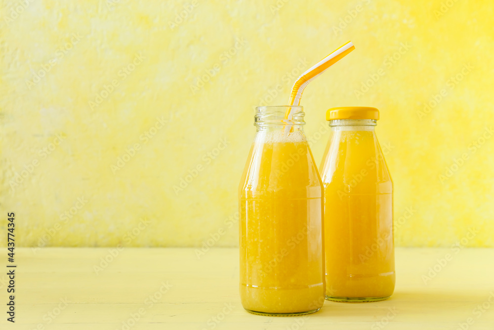 Bottles of tasty pineapple smoothie on color background Bottles of tasty pineapple smoothie on color background