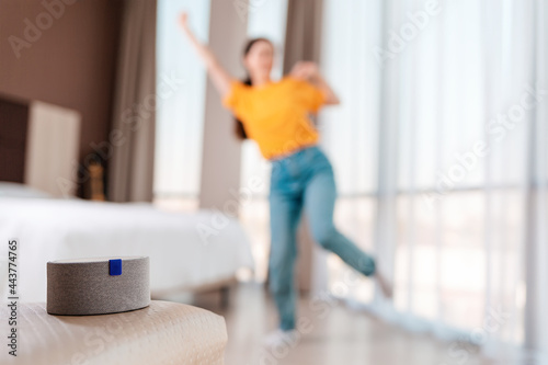 A portable smart gray speaker plays music. In the background, a woman dances in a blur. The concept of modern gadgets and entertaiment photo