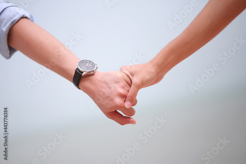 Young Asian couple holding hands walking on the beach. Close up image.