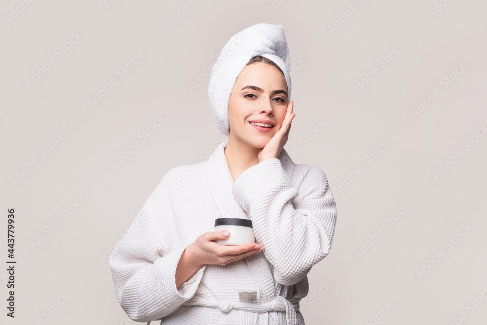Portrait of pleased girl putting cosmetic ointment on face while watching at mirror indoor. Glad female during skin care concept Portrait of pleased girl putting cosmetic ointment on face while watching at mirror indoor. Glad female during skin care concept