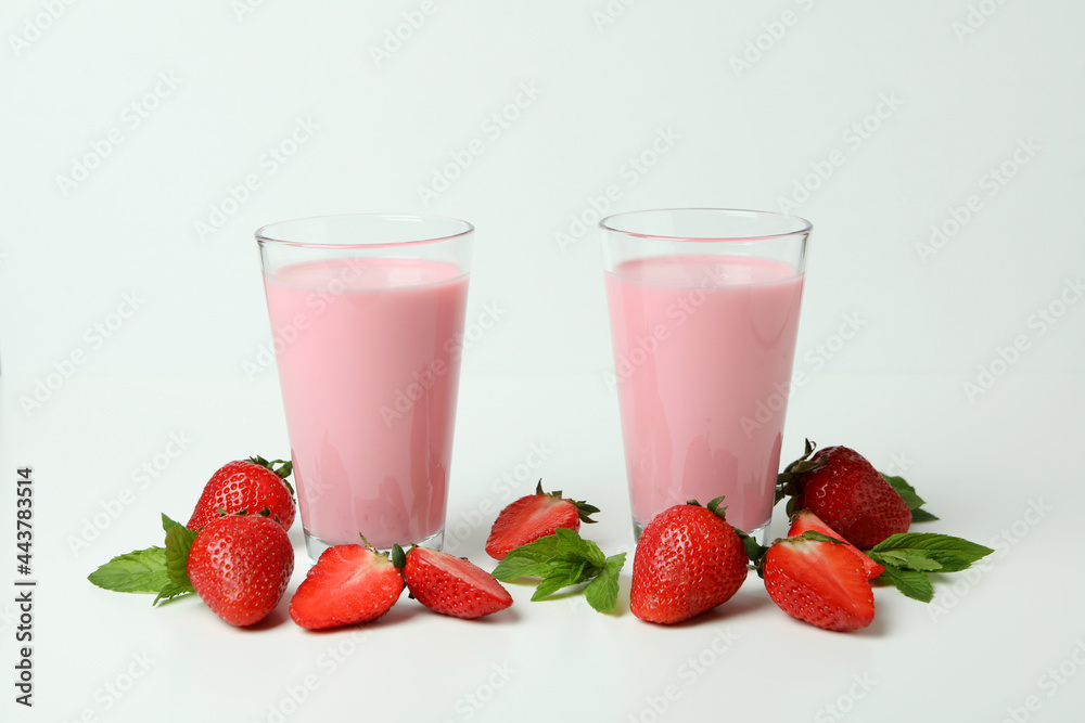 Glasses of strawberry milkshake and ingredients on white background Glasses of strawberry milkshake and ingredients on white background