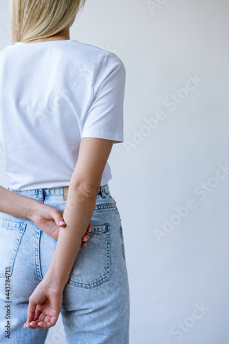 White T-shirt on a girl with white skin. The girl stands with her back and crossed her arms