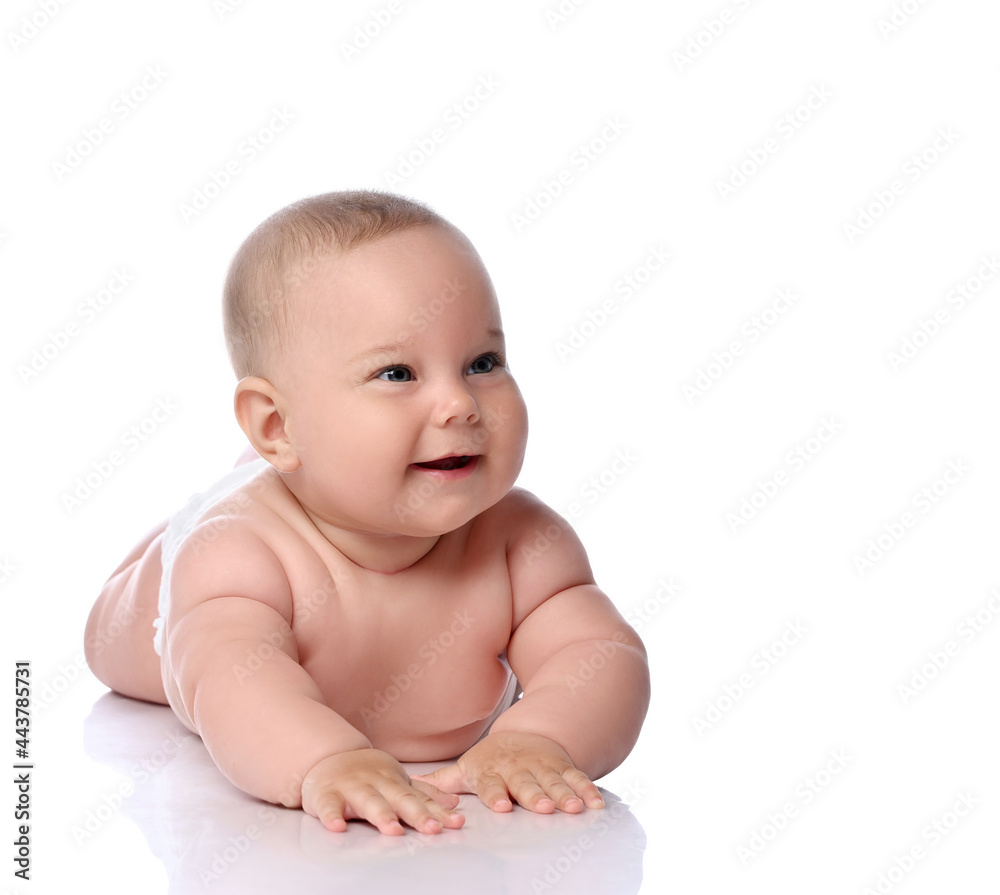 Happy infant child baby girl kid in diaper is lying on her tummy, stomach, crawling, laughing and giggling, looking aside at copy space isolated on a white background Happy infant child baby girl kid in diaper is lying on her tummy, stomach, crawling, laughing and giggling, looking aside at copy space isolated on a white background