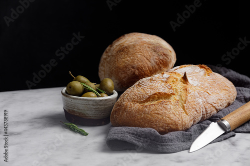 Rustic sourdough ciabatta bread with olives on a marble table. Freshly baked artisan ciabatta bread