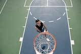 Young sportsman playing basketball on basketball court outdoor.