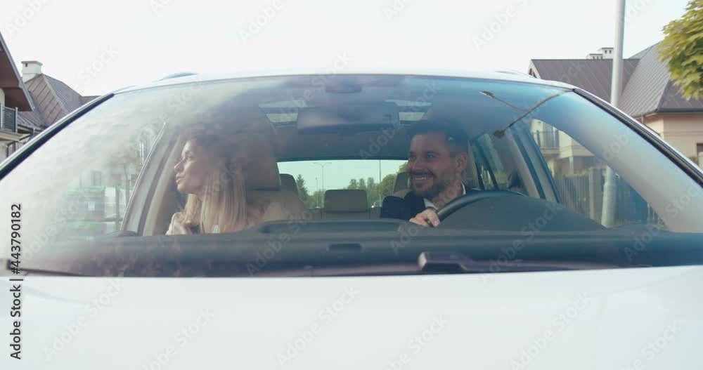 Enjoying fun travel. Beautiful young couple sitting on the front passenger seats and laughing while handsome man driving a car and chatting with somebody Enjoying fun travel. Beautiful young couple sitting on the front passenger seats and laughing while handsome man driving a car and chatting with somebody