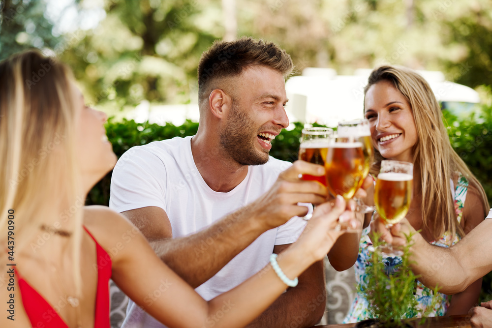 Group of happy friends toasting with beer at the summer bar Group of happy friends toasting with beer at the summer bar