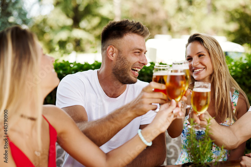 Canvas Print Group of happy friends toasting with beer at the summer bar