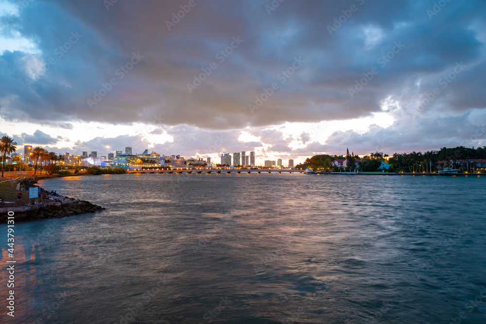 Miami, Florida cityscape skyline on Biscayne Bay. Panorama at dusk with urban skyscrapers and bridge over sea with reflection.