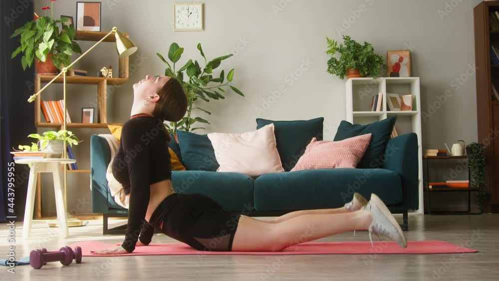 Young woman doing yoga exercises for keeping fit on floor in living-room. Self-isolation during coronavirus lockdown, sport remote education on the Internet. Healthy lifestyle concept, home gym. Young woman doing yoga exercises for keeping fit on floor in living-room. Self-isolation during coronavirus lockdown, sport remote education on the Internet. Healthy lifestyle concept, home gym.