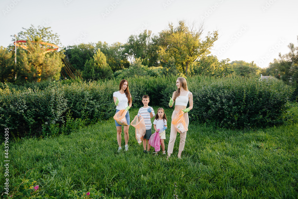 Obraz premium A group of girls with children at sunset are engaged in garbage collection in the park. Environmental care, recycling.