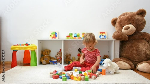 Happy cute child boy having fun playing with colorful wooden blocks on the floor, at home. Indoor activity for kids