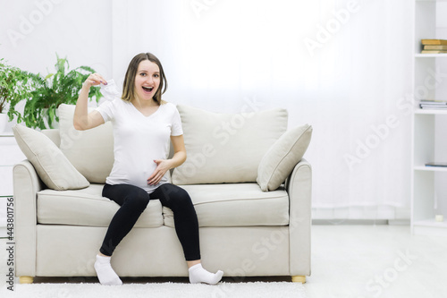 Free Download Pregnant woman touching her stomach and holding white socks. - GFXLoad