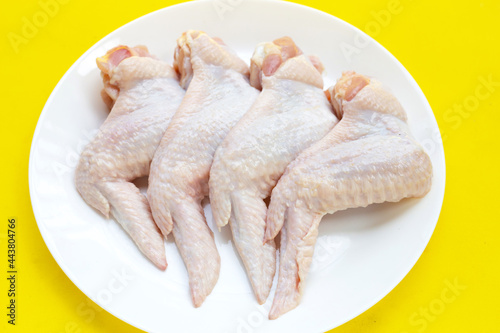 Fresh raw chicken wings in white platel on yellow background. photo