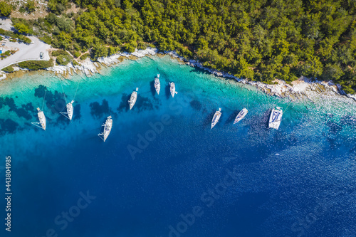 Sailing boats at anchor in blue bay of Fiskardo, Kefalonia island, Ionian, Greece. Aerial drone photo
