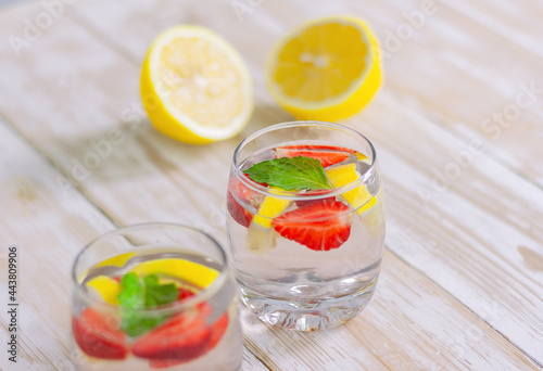 summer cocktail of citrus and berries. refreshing lemonade of strawberries, lemon and mint in two glasses on a light background.