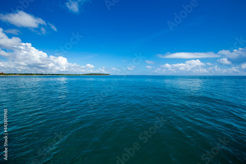 clouds on blue sky over calm sea with sunlight reflection