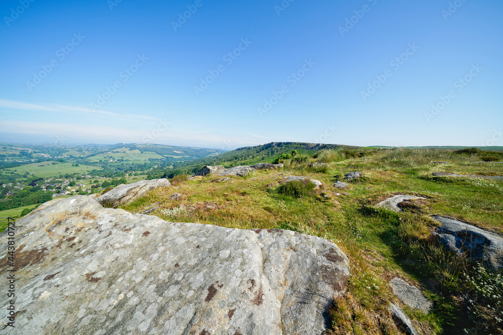 Over lichen covered slabs of gritstone rock and across to a distant hazy Curbar Edge Over lichen covered slabs of gritstone rock and across to a distant hazy Curbar Edge