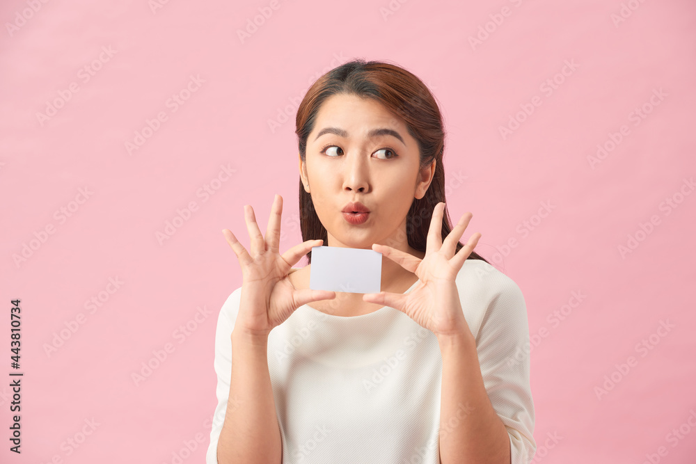 Happy excited amazed young woman holding credit card in hands and looking directly at camera