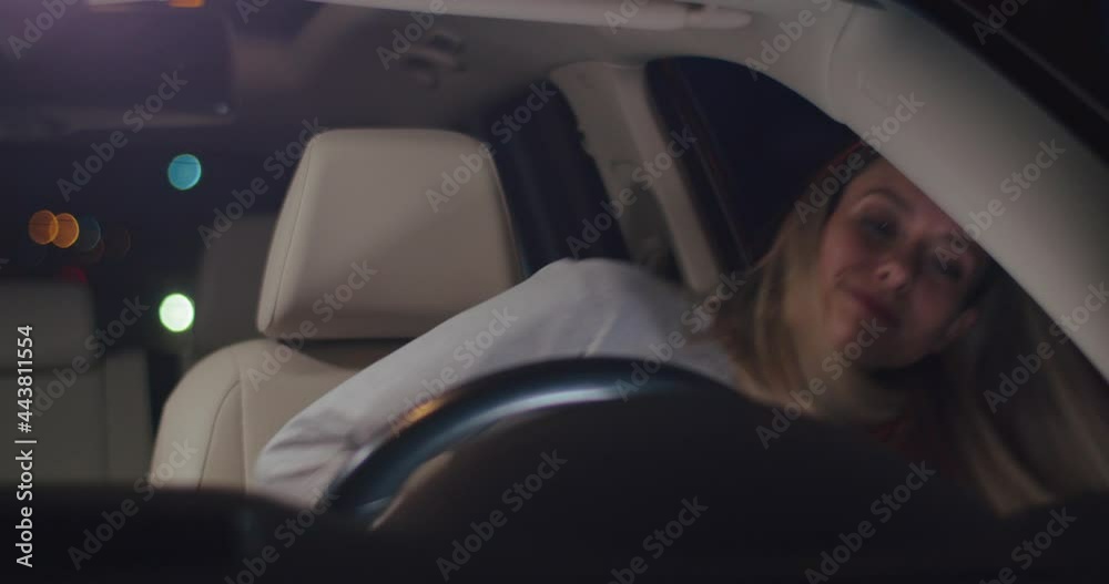 At the night. Front view of the caucasian blonde woman sitting into the car and fastened with safety belts while preparing to the traveling. People and transport concept