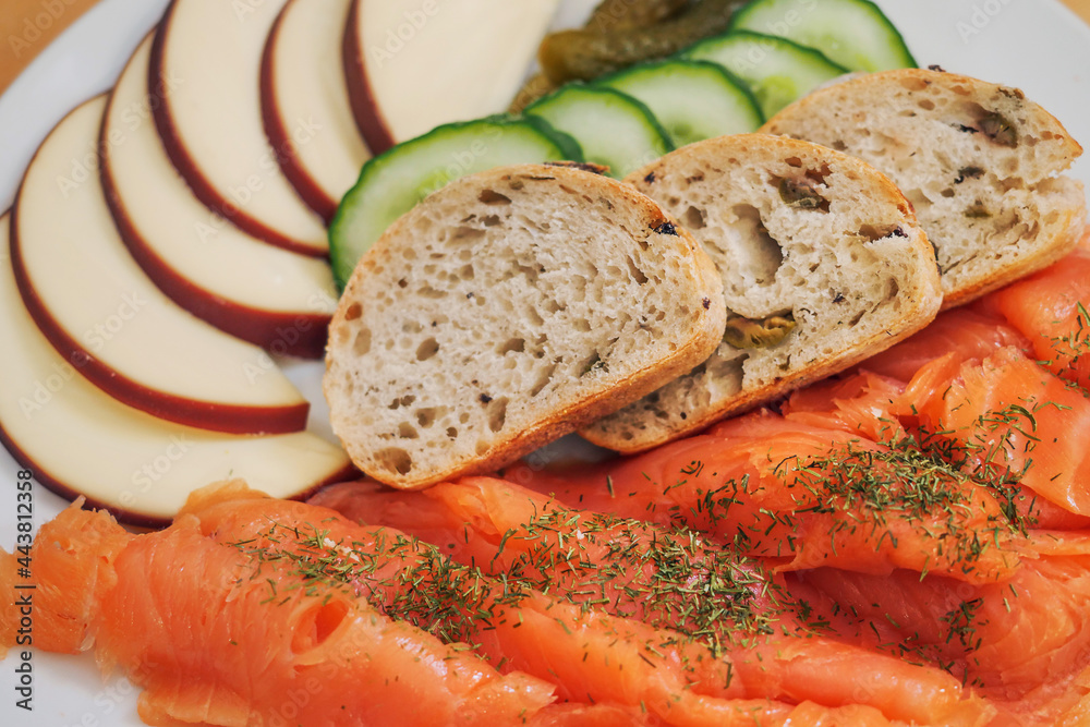 Plate with smoked salmon, slicec bread, fresh cucumbers and cheese. Serving of appetizer. Seafood, bakery product Plate with smoked salmon, slicec bread, fresh cucumbers and cheese. Serving of appetizer. Seafood, bakery product