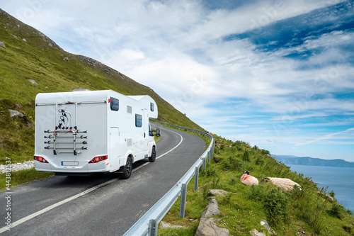 Motor home moving on a small narrow road in a mountains, sheep on a side of a road, Beautiful cloudy sky, Travel concept. Achill island, Ireland.