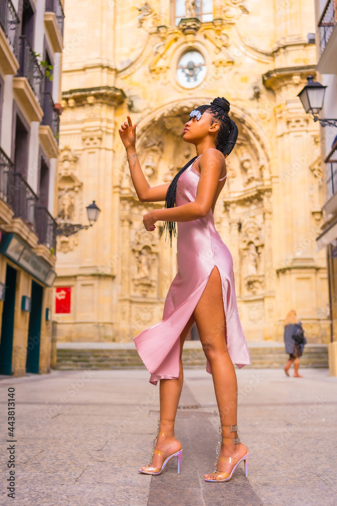 Naklejka premium Beautiful Dominican ethnic girl with braids with a beautiful pink dress. Fashion enjoying summer in a beautiful city church, vertical photo