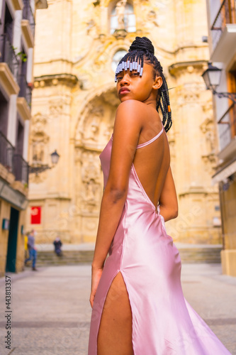 Dominican ethnic girl with braids with a beautiful pink dress. Fashion enjoying the summer in a beautiful church of the city, seductive look © unai